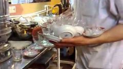 Официант разливает чай по 14 стаканам